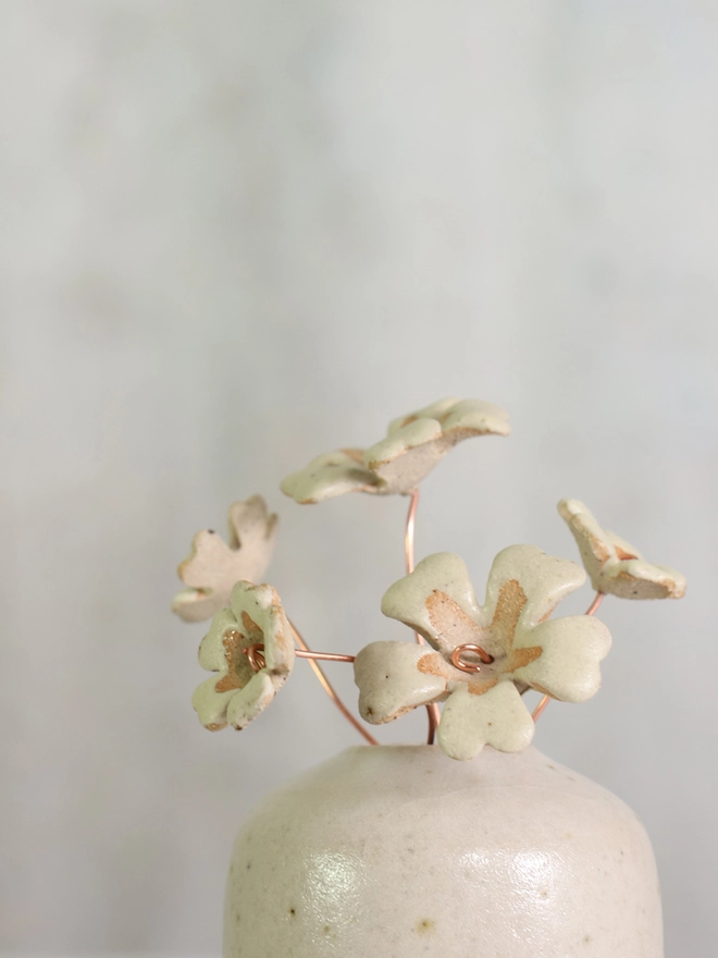 yellow handmade ceramic primroses protrude from a white flecked clay vase