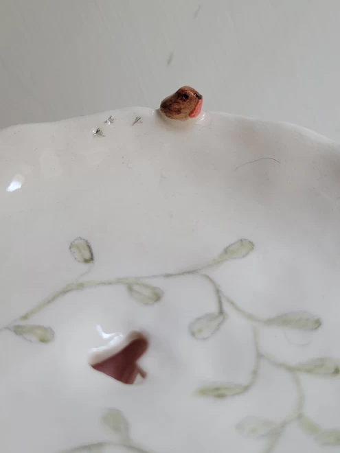 close up hand made ceramic soap dish with tiny robin bird bird prints and cut out heart with hand painted green botanical plant leaves 