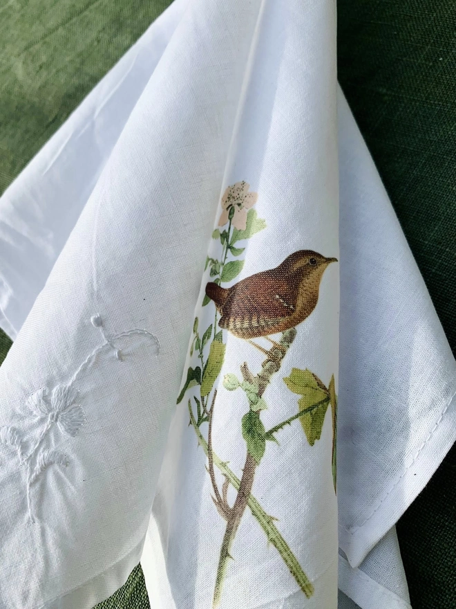 A white cotton napkin printed with a vintage illustration of a wren