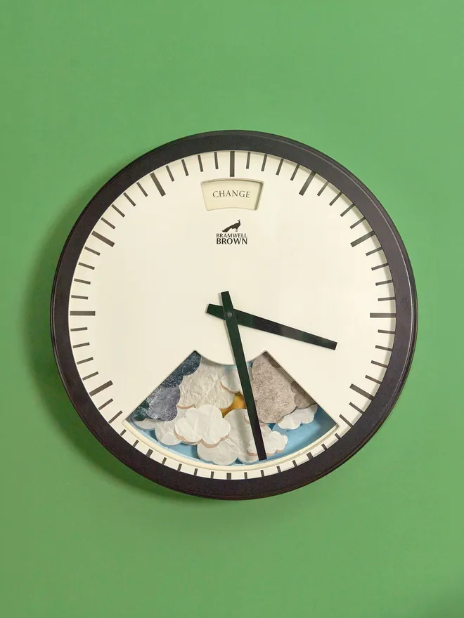 Bramwell Brown Art Clock, Black framed weather clock seen on a green wall 