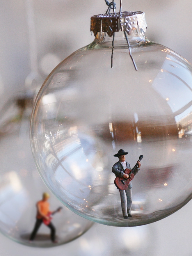 Miniature figure of an acoustic guitar player in a glass Christmas bauble