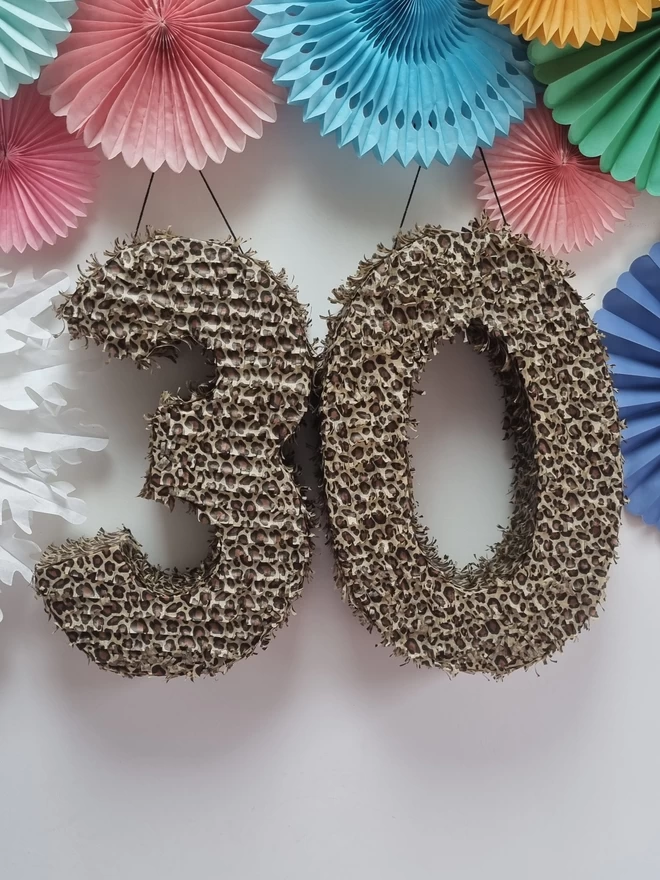 leopard print tissue paper fringed pinatas on a white background surrounded by pastel decorations