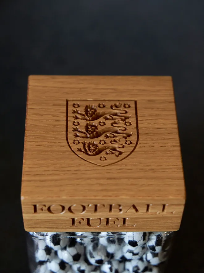 'Football Nuts' Oak Jar. A glass jar with an oak lid engraved with football nuts and the three lions crest, filled with sweets.