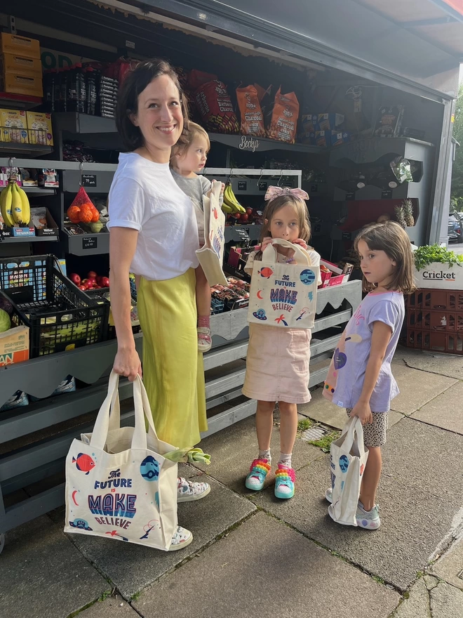 Mother two girls and a baby shopping with colourful reusable shopping bags 