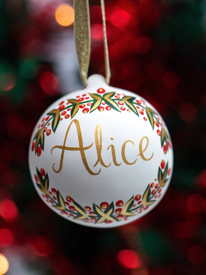 A personalised ceramic bauble with red berry wreath