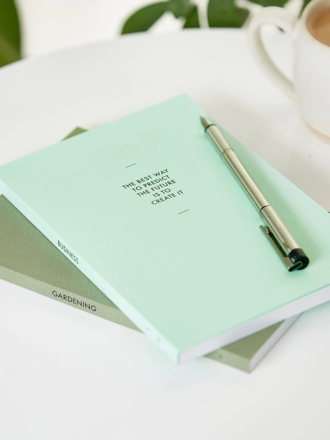 two green notebooks with personalised text on the cover