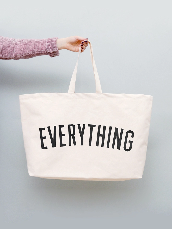 Hand holding out the Everything oversized tote bag in natural canvas