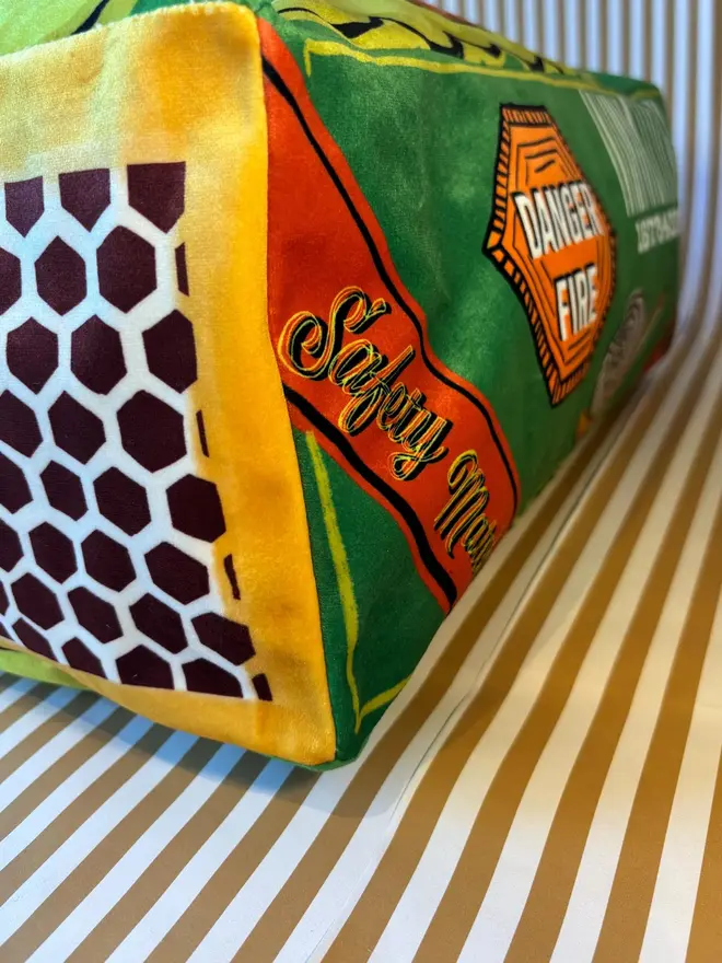 Snail Matchbox Cushion, a green decorated cushion sitting on a decorated surface. 