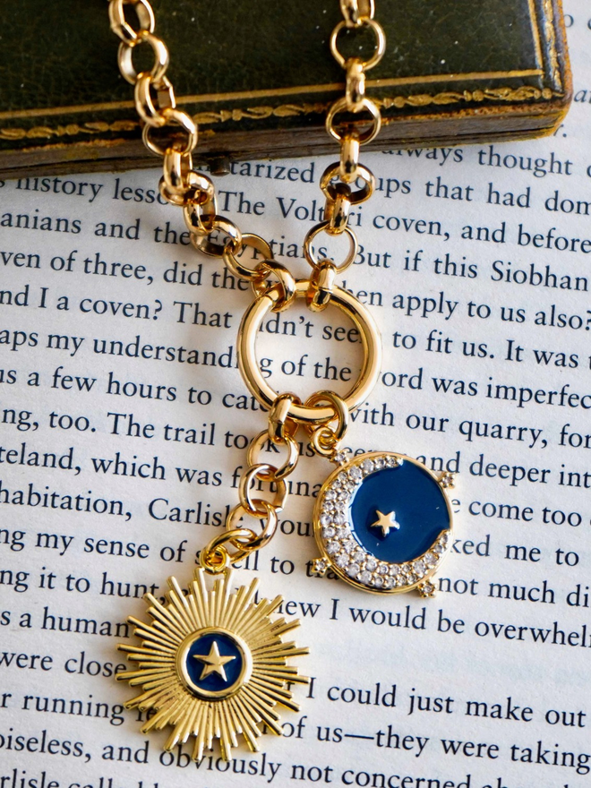 Gold and blue enamel moon and star charms hanging from a chunky gold belcher chain necklace