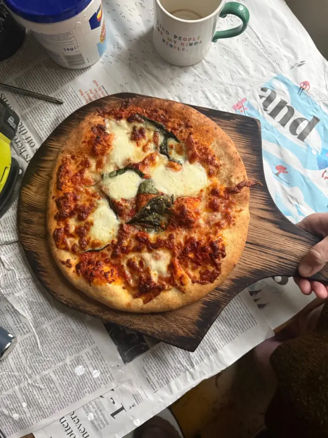Hand holding pizza board styled o newspaper taking a tea break