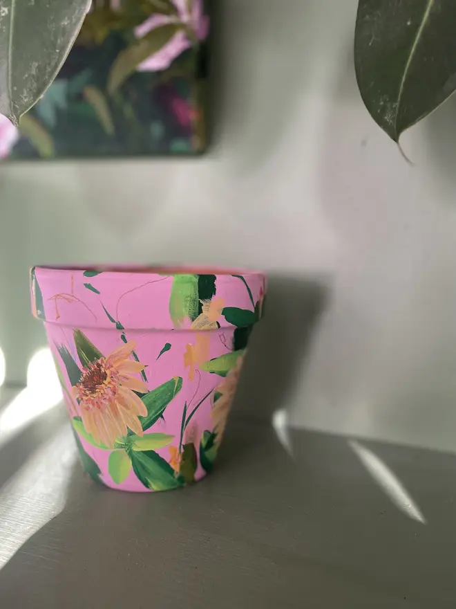 hand painted floral terracotta plant pot subtle pink background with apricot Zinderella Lilac flowers 