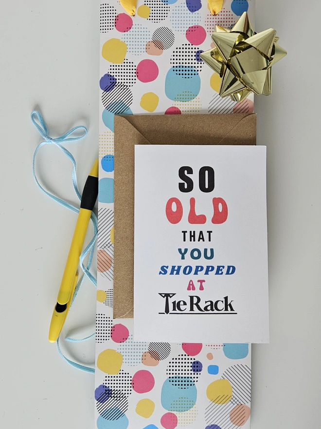 A photograph of the front of a humorous A6 greeting card illustrated using brightly coloured text and the retro shop logo. The text says so old you shopped at Tie Rack