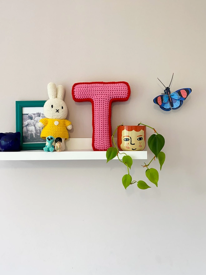 Crocheted Letter T in Bubblegum Pink and Postbox Red, on a childs shelf