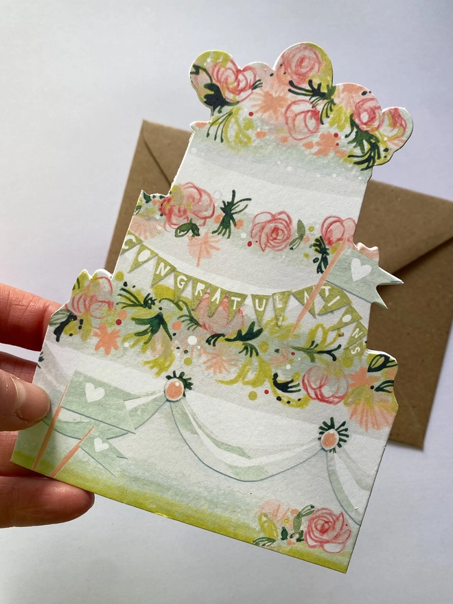 Esther kent illustrated greetings card in the shape of a tierd cake decorated with pink flowers and greenery. d