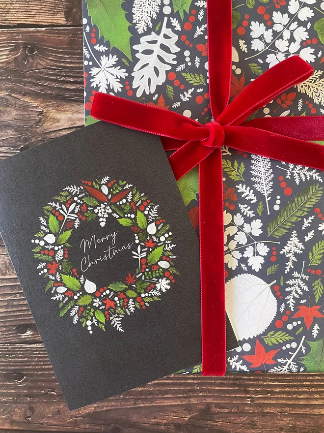 Christmas Card on Dark Wood with Matching Gift Wrap in a Pressed Holly and Ivy Design with Red Velvet Ribbon