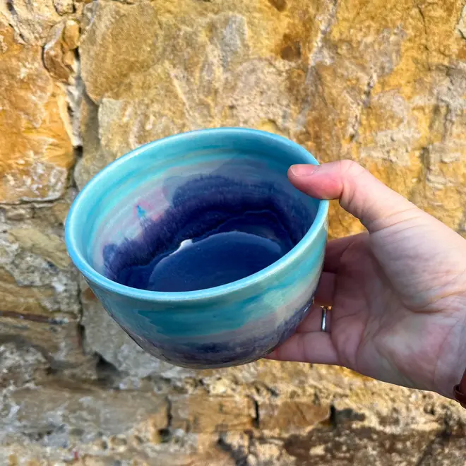 Landscape Small Bowl, a colourful bowl held against a brick backdrop. 