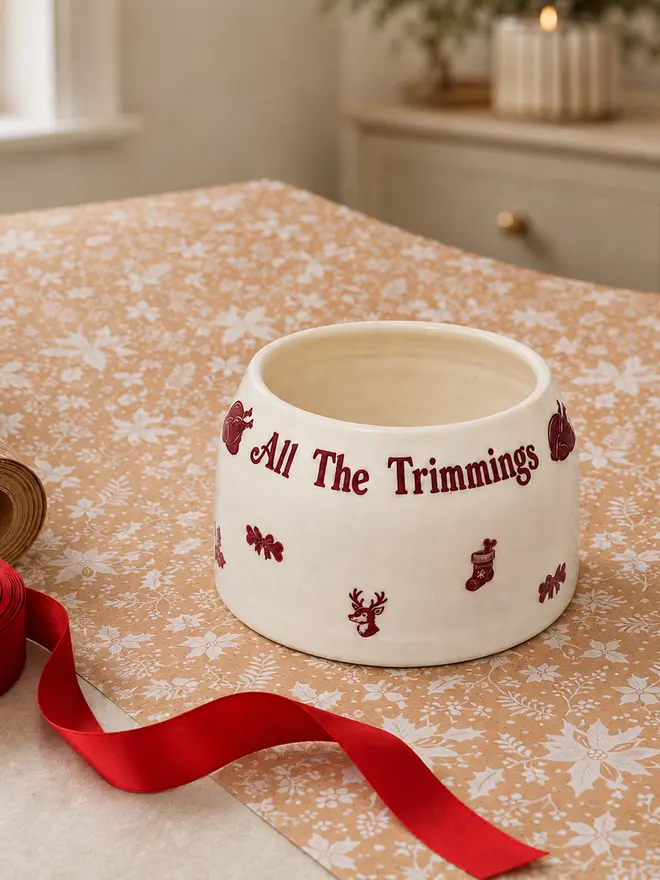All The Trimmings handmade ceramic spaniel bowl displayed with kraft Christmas gift wrap and loose red satin ribbon, ready to be wrapped.