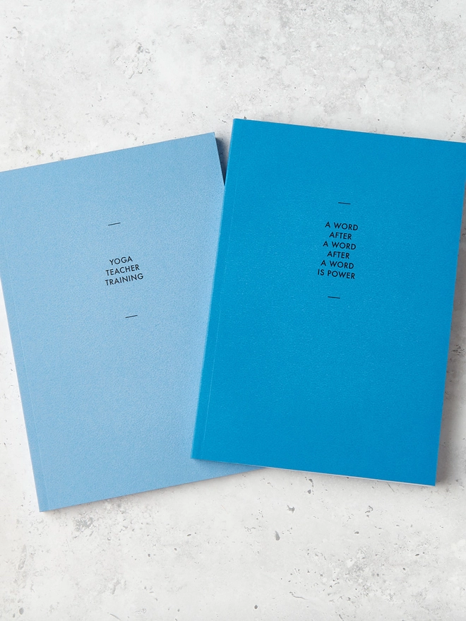 two blue notebooks with personalised text on the cover