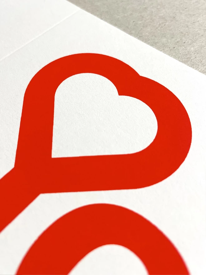 close up of a heart designed into  the top of a Y, screenprinted in red ink on white card.