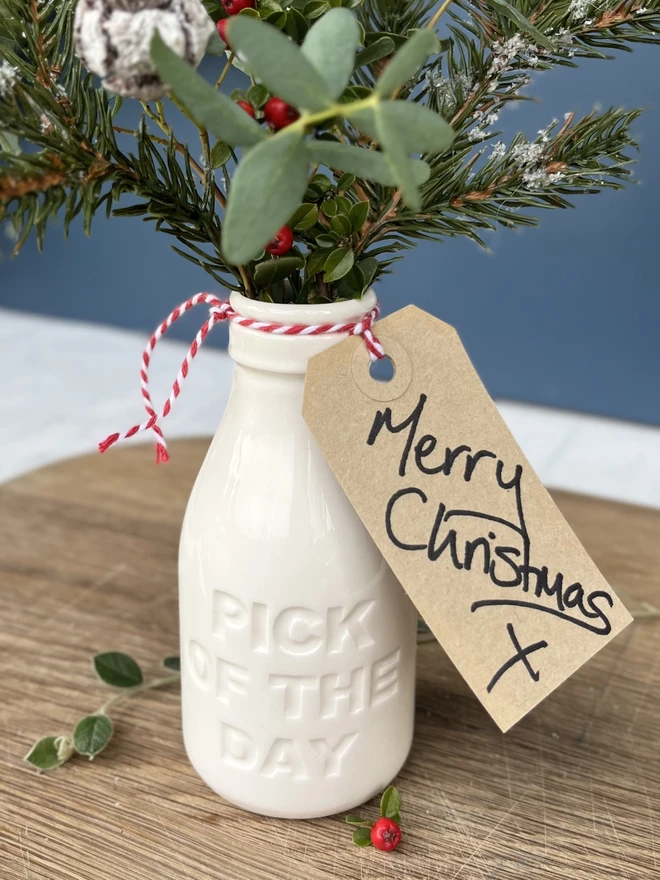 Handmade ceramic pick of the day bottle filled with Christmas foliage tied with a tag ready for gifting