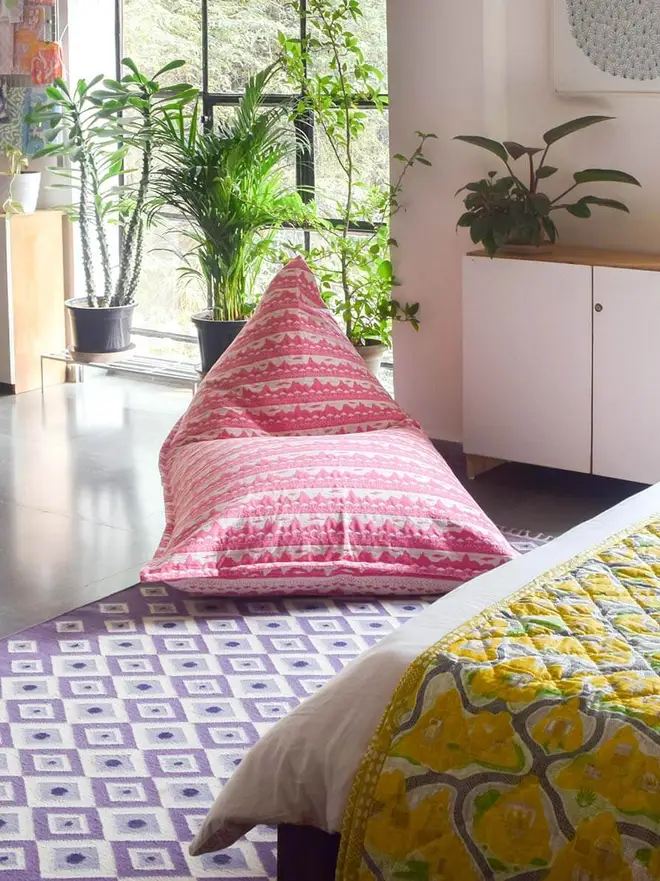 Pink Belle Mare Woven Bean Bag Cover, a pink bean bag sitting in a decorated room. It is accompanied by other colourful items. 