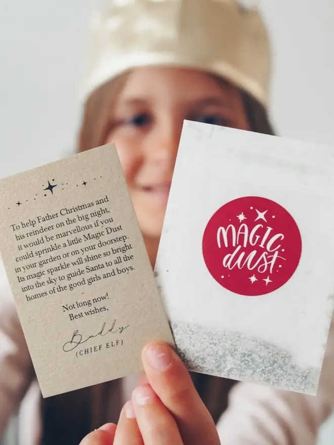 A child holding the Chief Elf note and the red Magic Dust glitter packet.