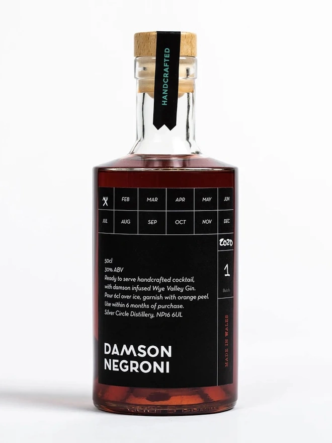 Damson Negroni , a bottle of negroni on a white surface. 