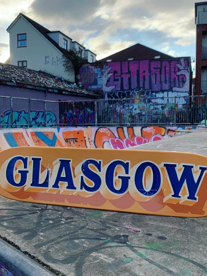 'Glasgow' on an orange board with blue lettering, beige and orange shades.