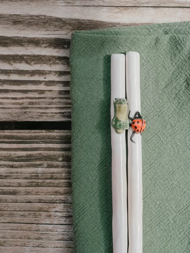 Frog and ladybird straws seen together on a green napkin.