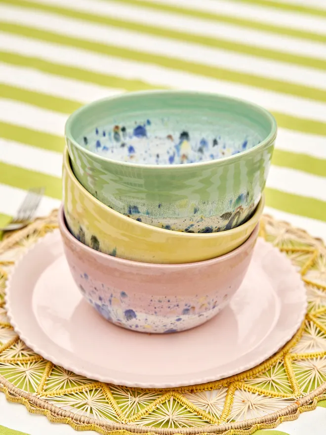 Shoreline Ramen Bowl, a collection of colourful ramen bowls stacked together-green, yellow and pink, placed on a green and white striped tablecloth 