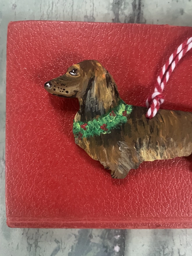 Long - Haired Dachshund Christmas Tree Decoration placed on a book about dogs
