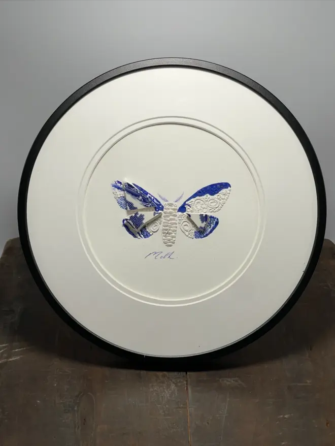 Hand-drawn, painted, mosaic clay, vintage Chinese willow tree pottery insect on white double mounted card, in a black circular frame.