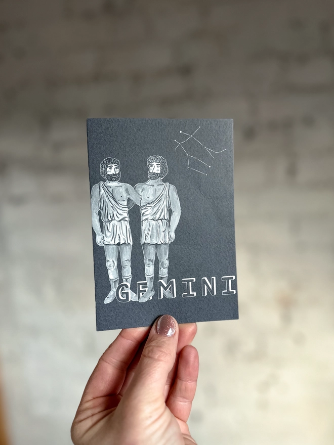 a greetings card featuring a greyscale illustration of a zodiac style twins with the text “GEMINI”