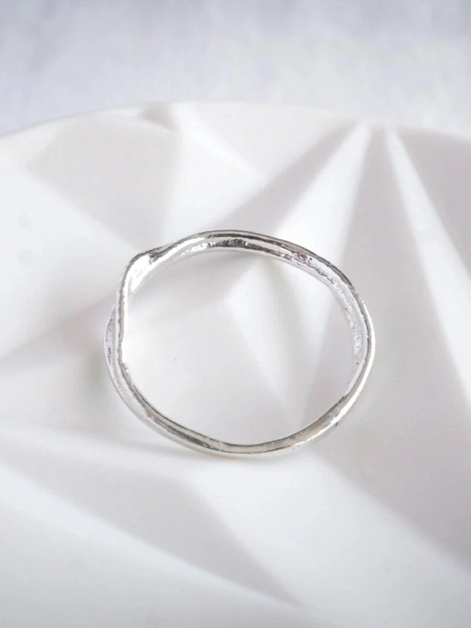 Silver Organic Stacking Ring on a silk material