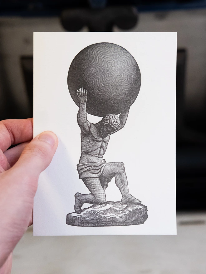 Letterpress card with design printed thereupon. The Titan Atlas holding one of the celestial spheres, shaded with parallel lines.