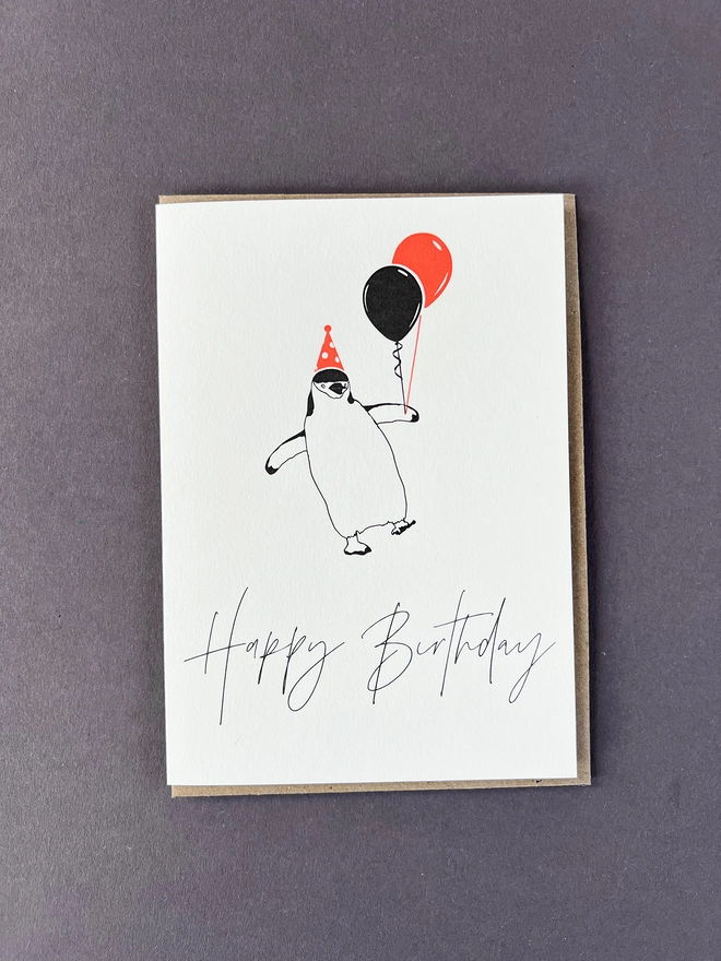 A cheeky, fun loving penguin in an neon orange party hat, holding balloons with "Happy Birthday" beautifully written in a modern calligraphy underneath.