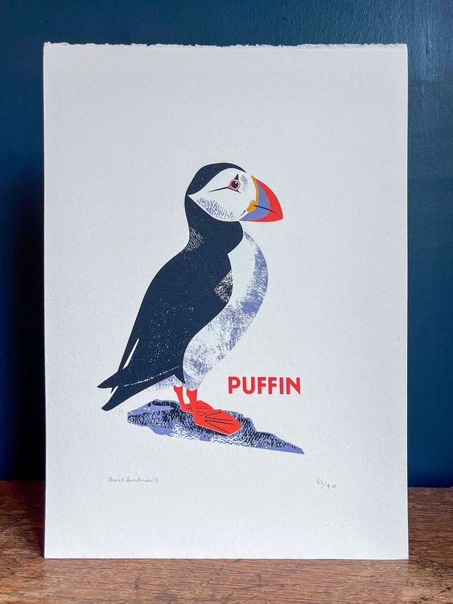A screenprint of a Puffin on white paper against a navy blue background.