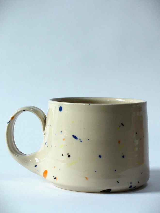 Small creamy white terrazzo cups with black, blue, and yellow splatters and glossy glaze