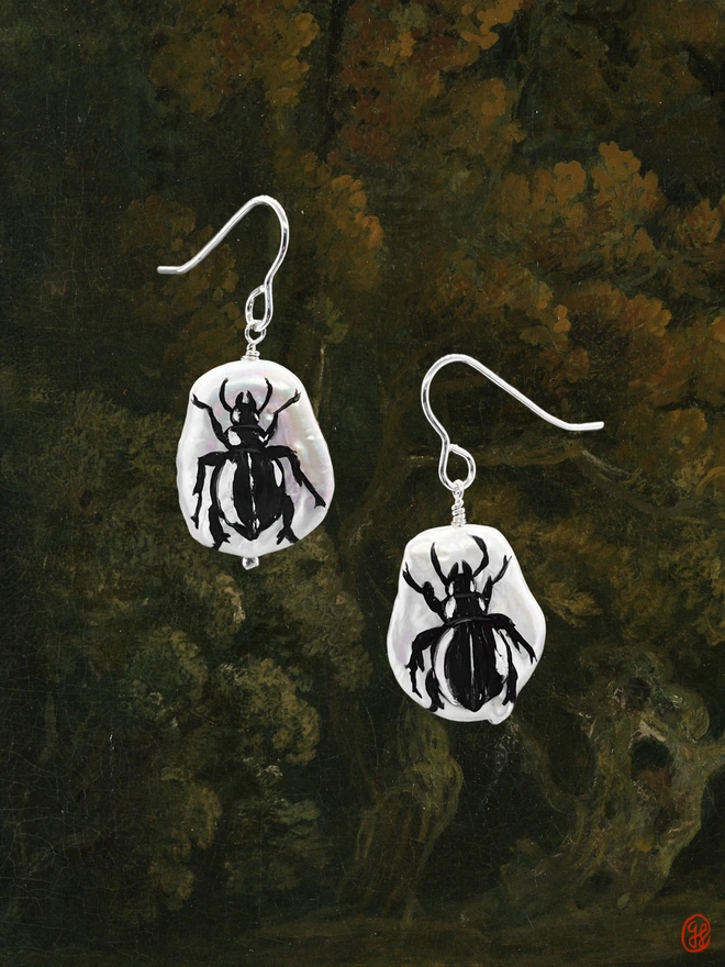 A pair of flat pear shaped pearl earrings set in sterling silver with hand painted black beetle motif of each.