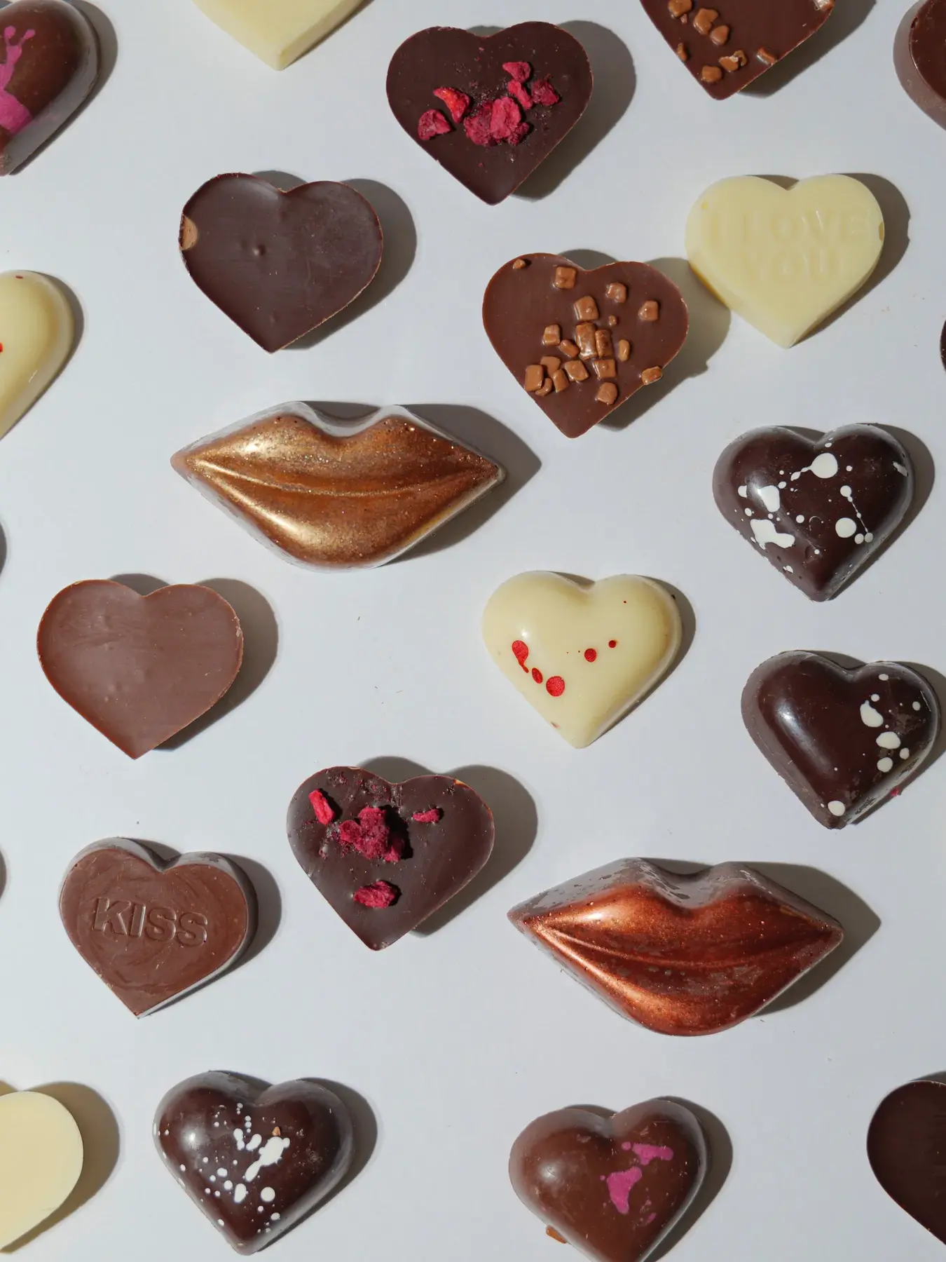 A range of chocolates heart cube scattered on a white table. 