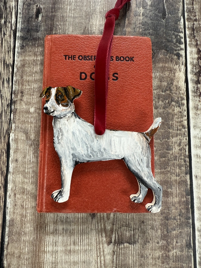 Smooth Haired Jack russell wooden Dog  Christmas Decoration With Red ribbon placed on a small book about dogs