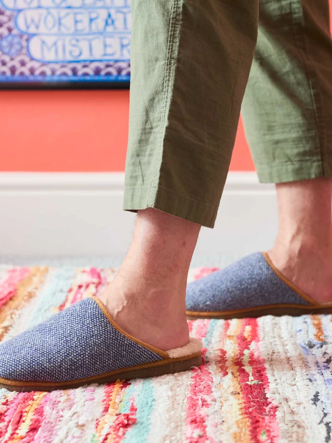 MAN WALKING IN NAVY BLUE CHECKED SLIPPERS IN FRONT OF A CORAL WALL