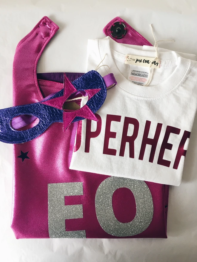 folded superhero costume - pink personalised cape, white superhero t-shirt, purple & pink star superhero mask 