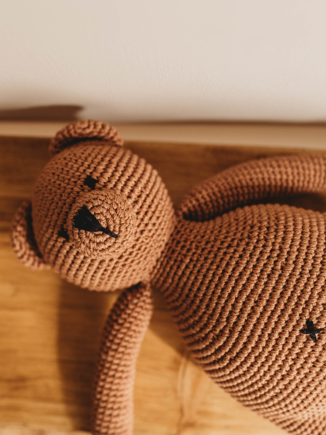 handmade brown crochet teddy bear on wooden shelf