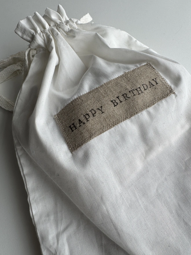 White drawstring bag with Happy Birthday label on