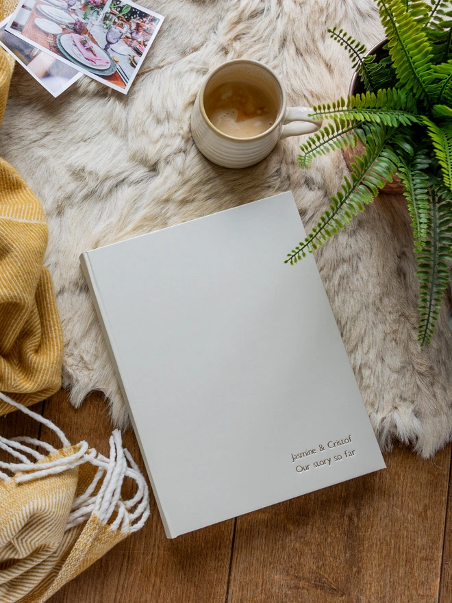 There is a cosy feel to the image and on a sheepskin rug there is a white A4 album which has been personalised with two names.
