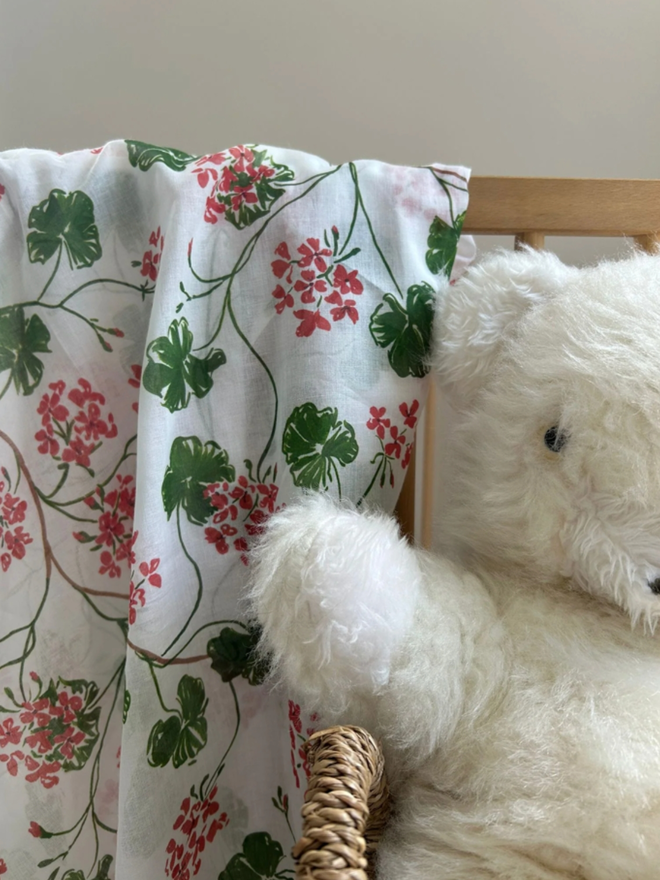 Geranium Muslin. A muslin draped over a chair, patterned with green and pink flowers.