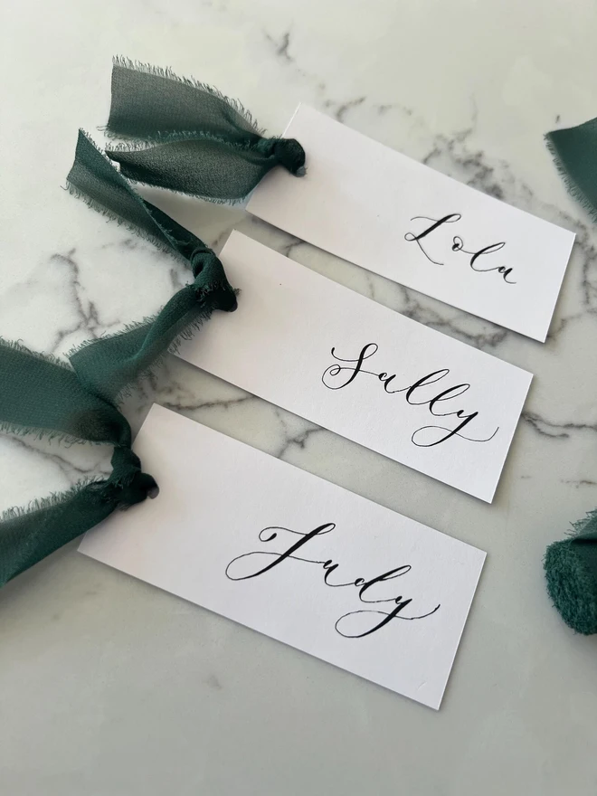 Personalised Calligraphy Wedding White Place Cards, white place cards with forest green ribbon. 
