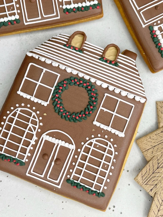 Hand-iced Christmas gingerbread house biscuit, individually wrapped for festive gifting.