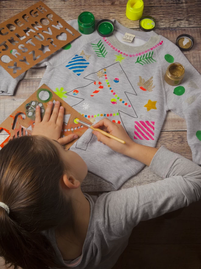 Girl designing and printing onto her own xmas swetashirt with stencils and inks